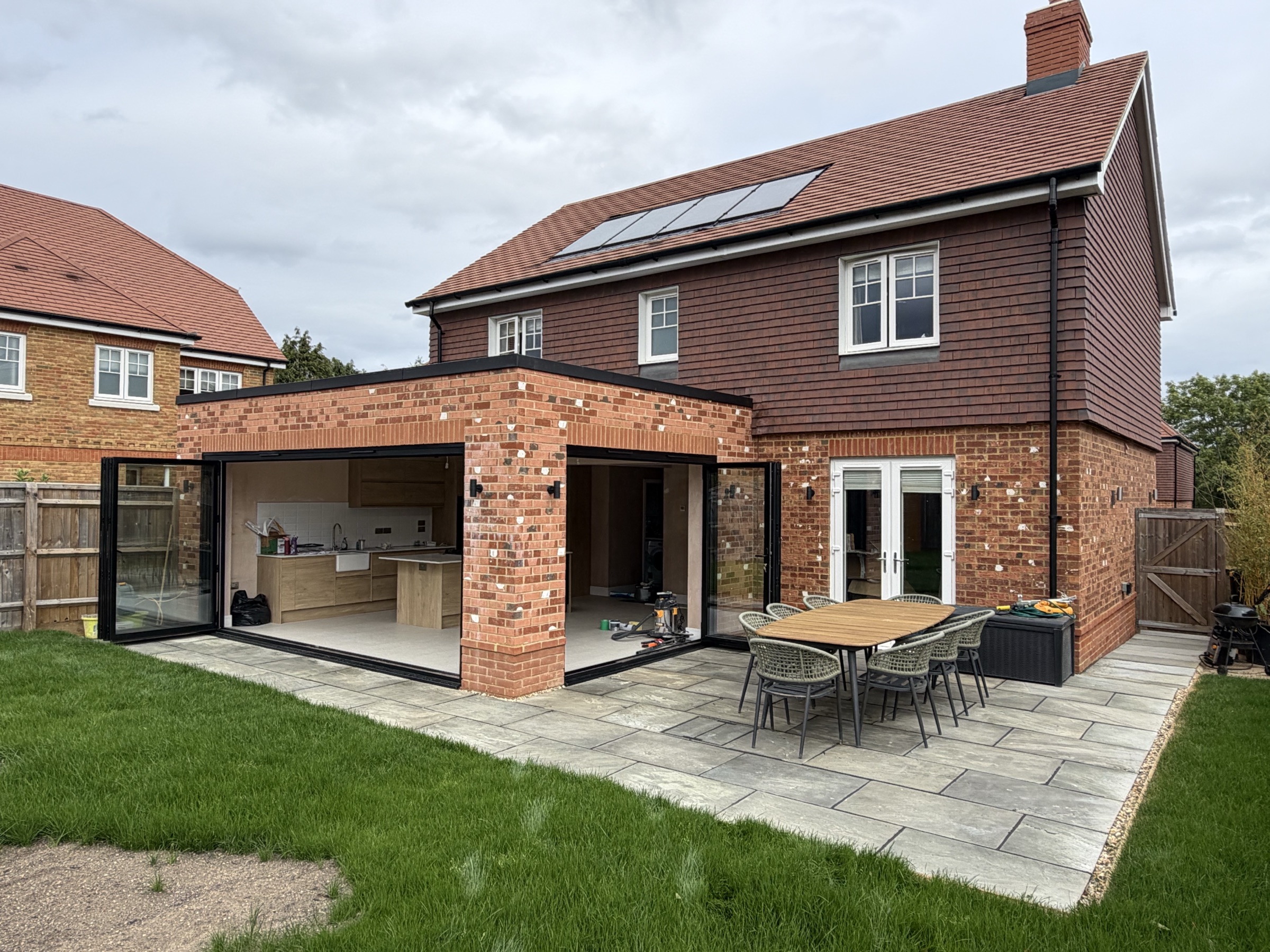 Black aluminium bi-fold doors fully open on a brick extension