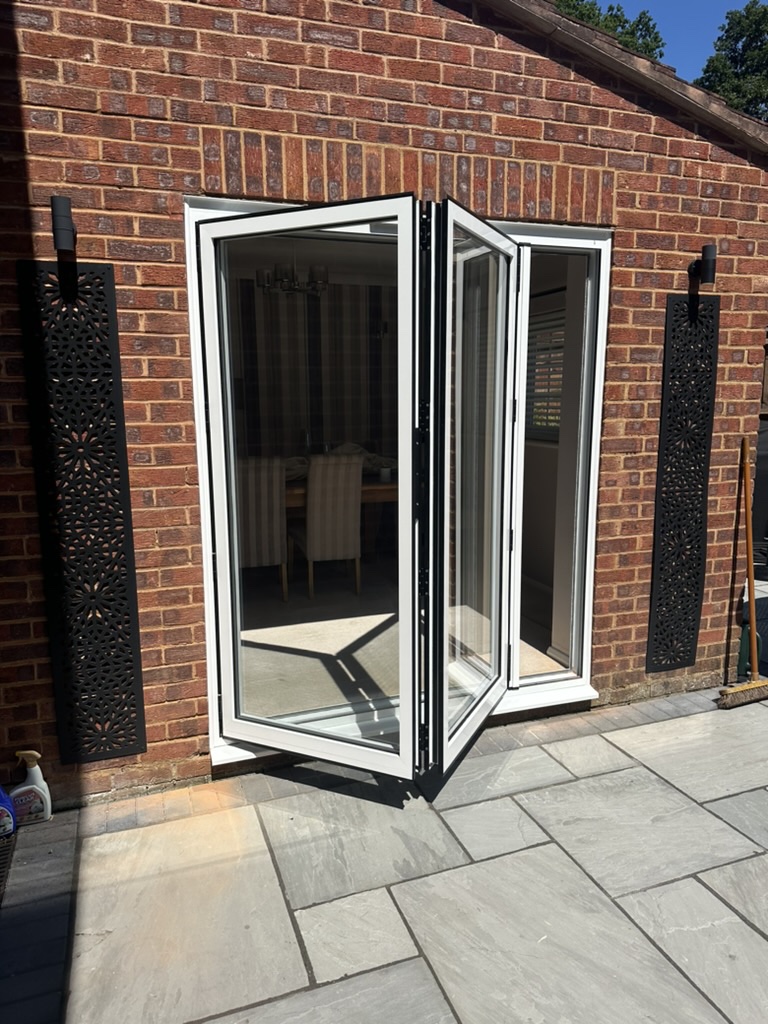 White UPVC bi-fold doors partly open on a brick wall