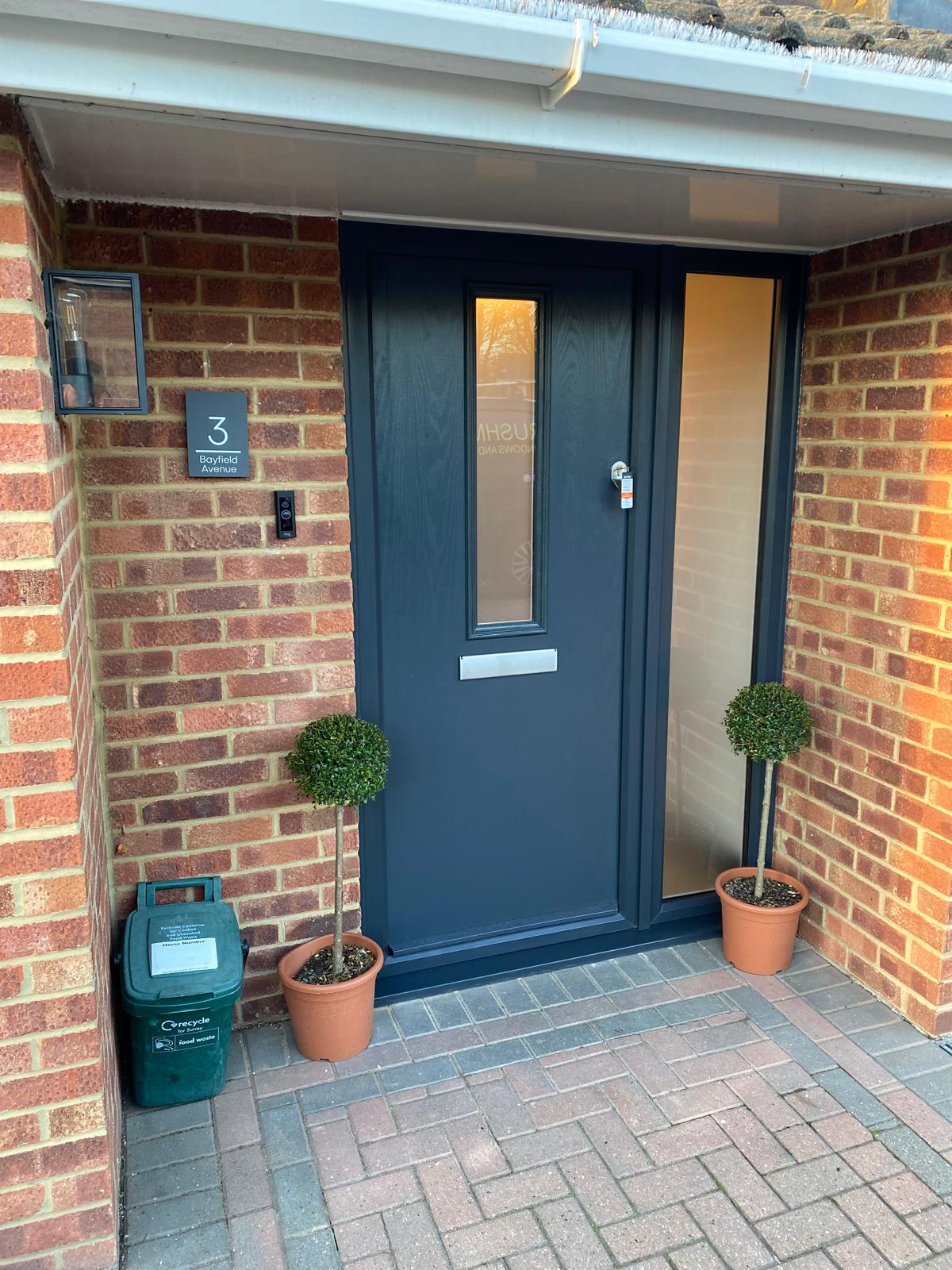 Anthracite composite front door with topiary either side