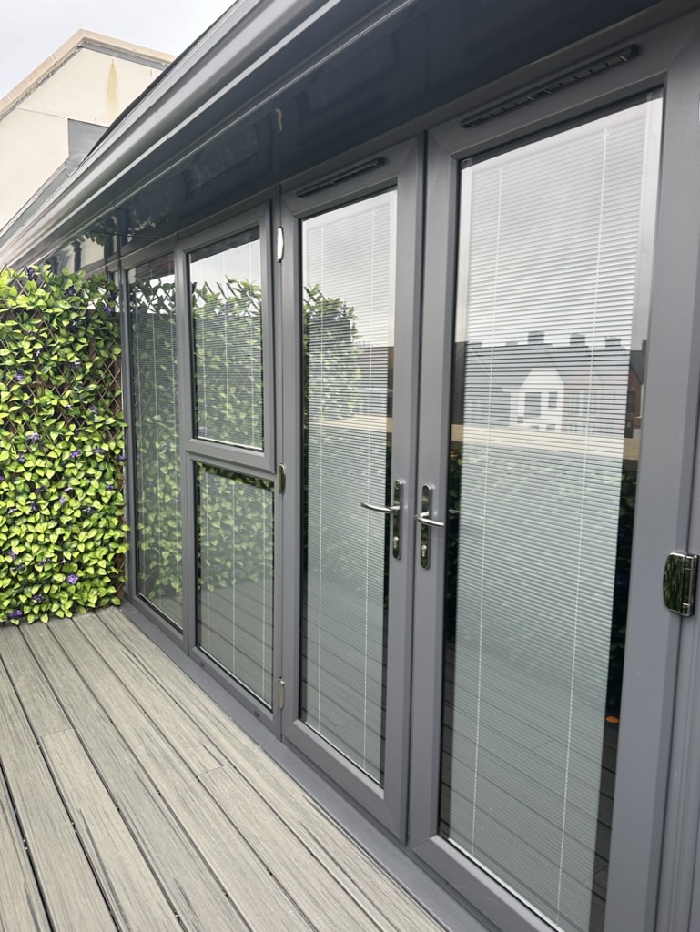 Grey french doors with integral blinds opening onto a terrace