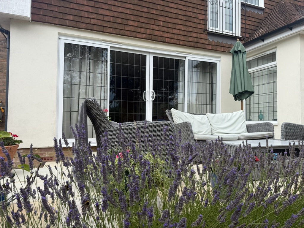 White UPVC sliding patio doors with leaded glazing opening onto a garden terrace