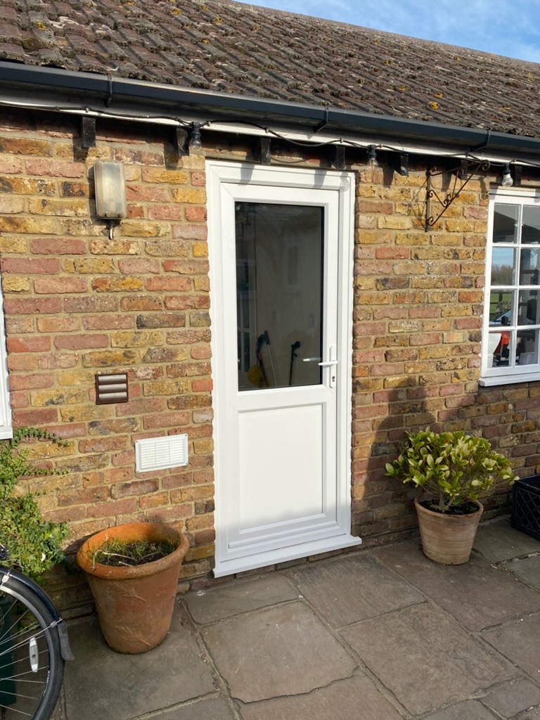 White UPVC door with full glass panel on a brick cottage