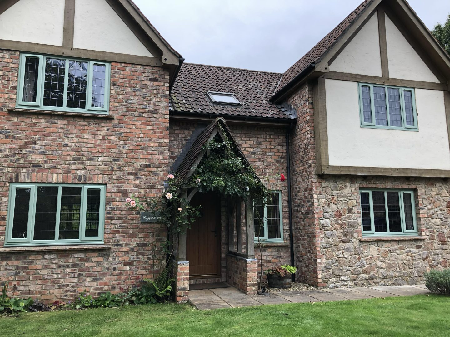 Green UPVC casement windows on a traditional brick cottage